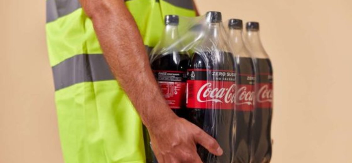 Sixpack van Coca Cola flessen, gedragen door een medewerker